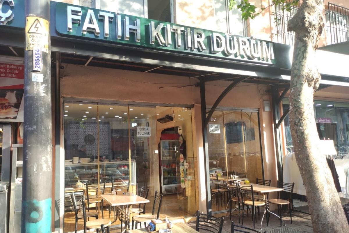 Fatih Kıtır Dürüm restoranının bahçesinin genel görünümü. Müşterilerin açık havada yemek yiyebileceği masalar ve bitkilerle dekore edilmiş huzurlu bir ortam.